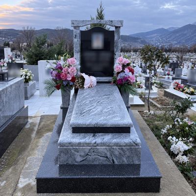 Grave with black headstone and multicolor granite frame