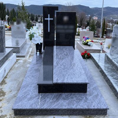 Granite grave with a black headstone and a cross