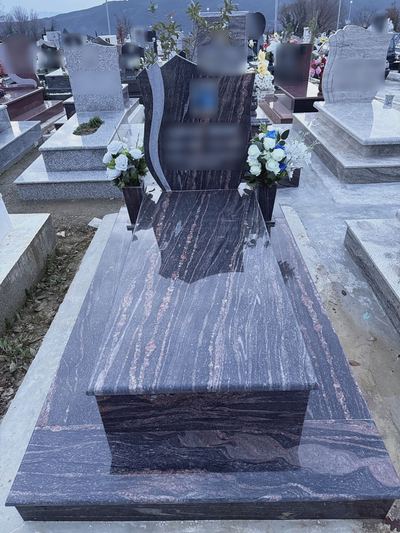 Finished granite grave with headstone and white flowers